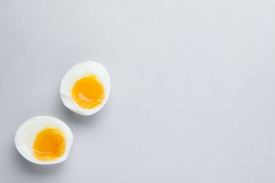 Photo of Halves of fresh soft boiled egg on white background, flat lay. Space for text