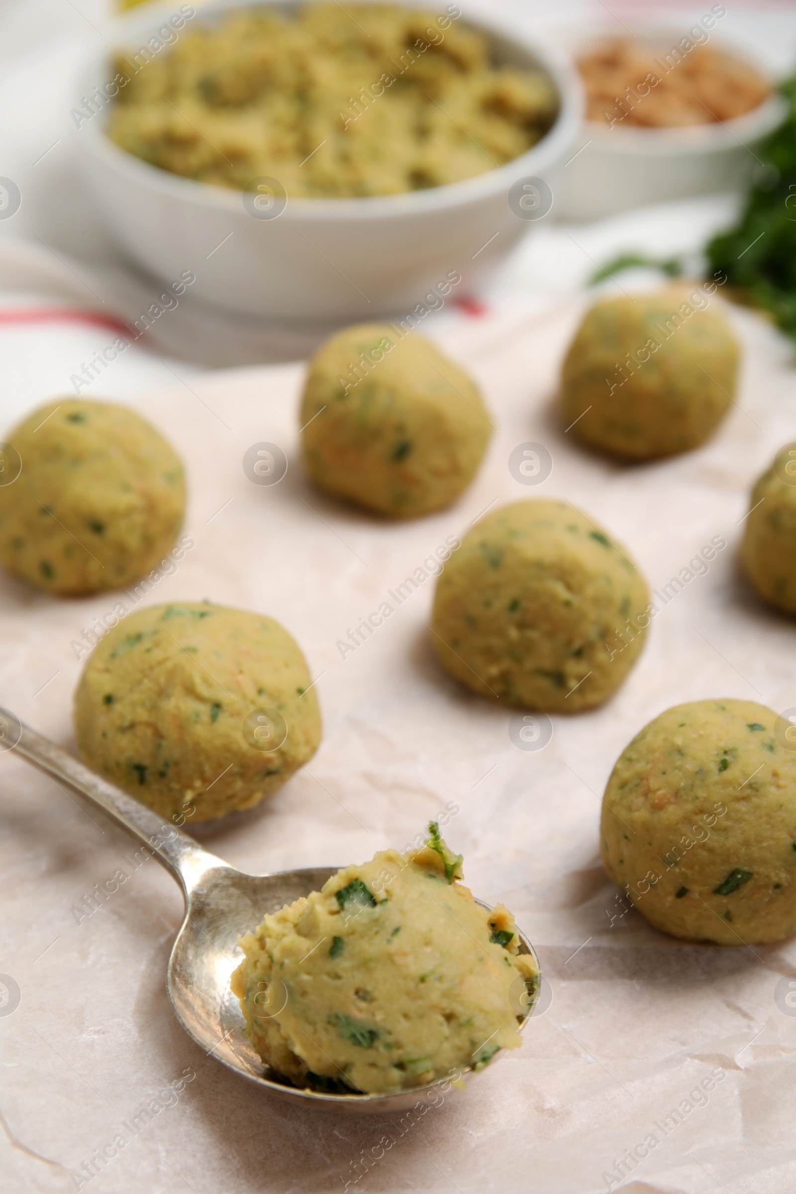 Photo of Raw falafel balls and spoon on parchment, closeup