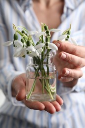 Photo of Woman holding glass jar with snowdrops, closeup