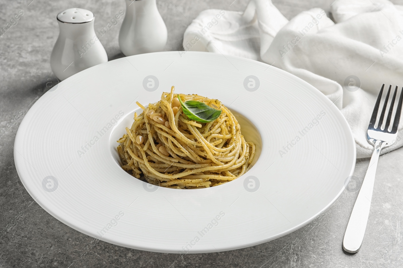 Photo of Plate of delicious basil pesto pasta served for dinner on table