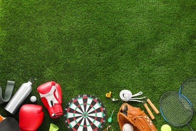 Photo of Different sport equipment on green grass, flat lay. Space for text