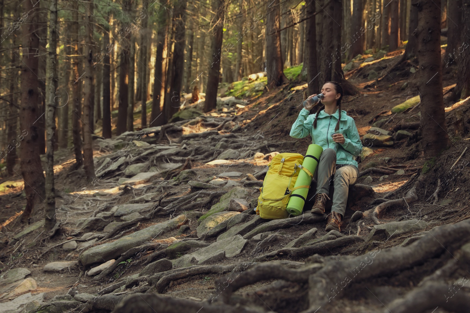 Photo of Tourist with backpack drinking water in mountain forest