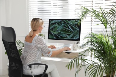 Photo of Woman working on computer at table in room. Interior design