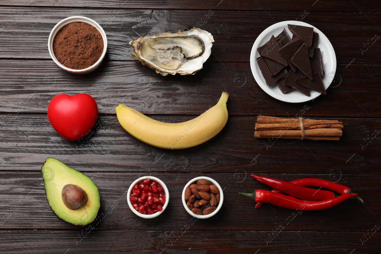 Photo of Natural aphrodisiac. Different food products and red decorative heart on dark wooden table, flat lay