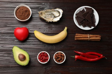 Photo of Natural aphrodisiac. Different food products and red decorative heart on dark wooden table, flat lay