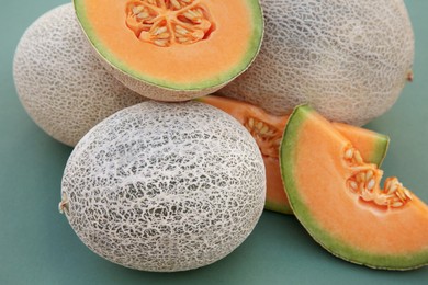 Photo of Whole and cut fresh ripe cantaloupe melons on teal background, closeup