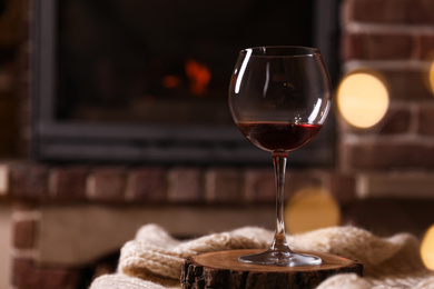 Glass of wine near fireplace indoors. Space for text