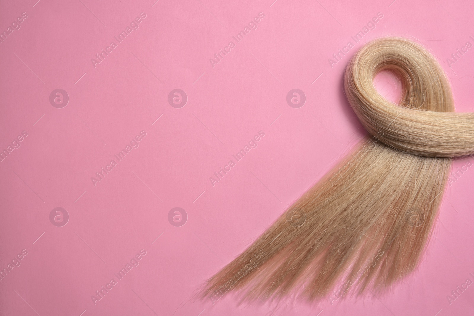 Photo of Lock of blond hair on color background, top view. Space for text