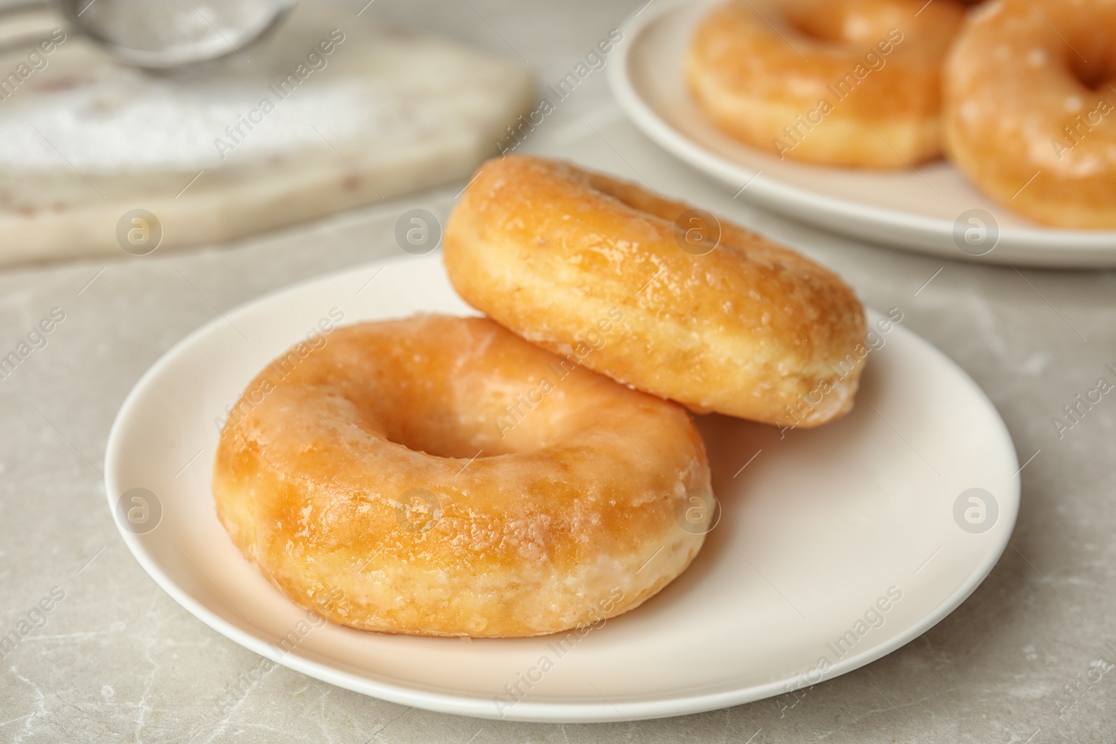 Photo of Sweet delicious glazed donuts on light table