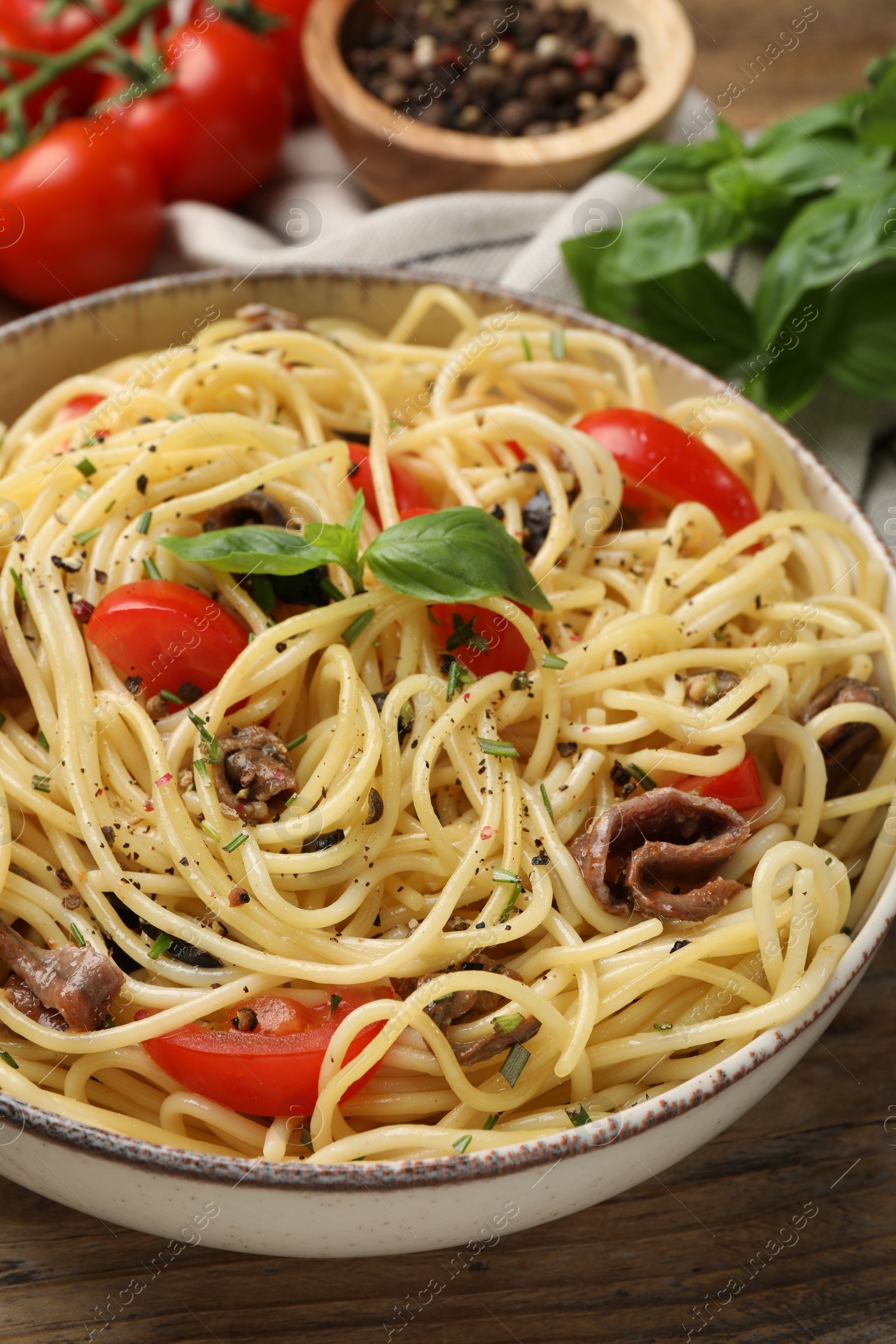 Photo of Delicious pasta with anchovies, tomatoes and spices on wooden table