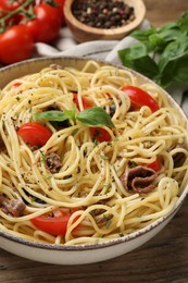 Photo of Delicious pasta with anchovies, tomatoes and spices on wooden table