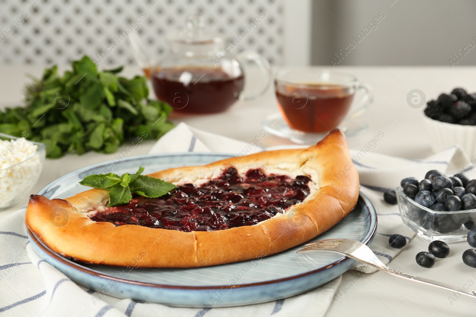 Photo of Delicious sweet cottage cheese pastry with cherry jam on white table