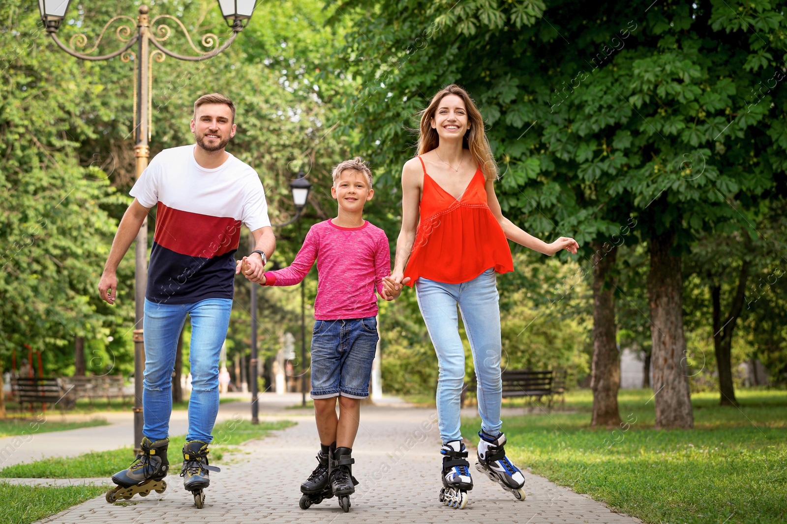 Photo of Young happy family roller skating in summer park