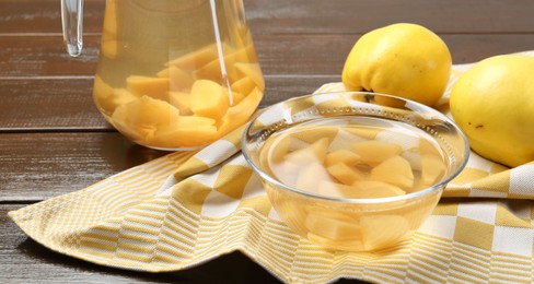 Photo of Delicious quince drink and fresh fruits on wooden table, closeup