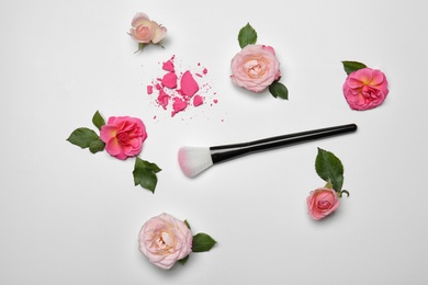 Flat lay composition with makeup brush and flowers on white background