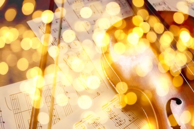 Image of Christmas and New Year music. Violin and music sheets on wooden background, bokeh effect