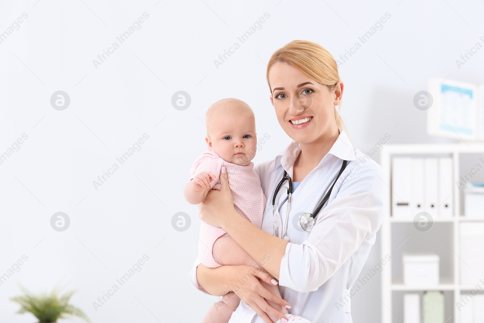 Photo of Children's doctor with cute baby in hospital. Space for text