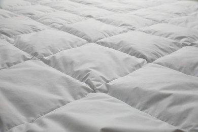 Photo of Soft quilted blanket as background, closeup view