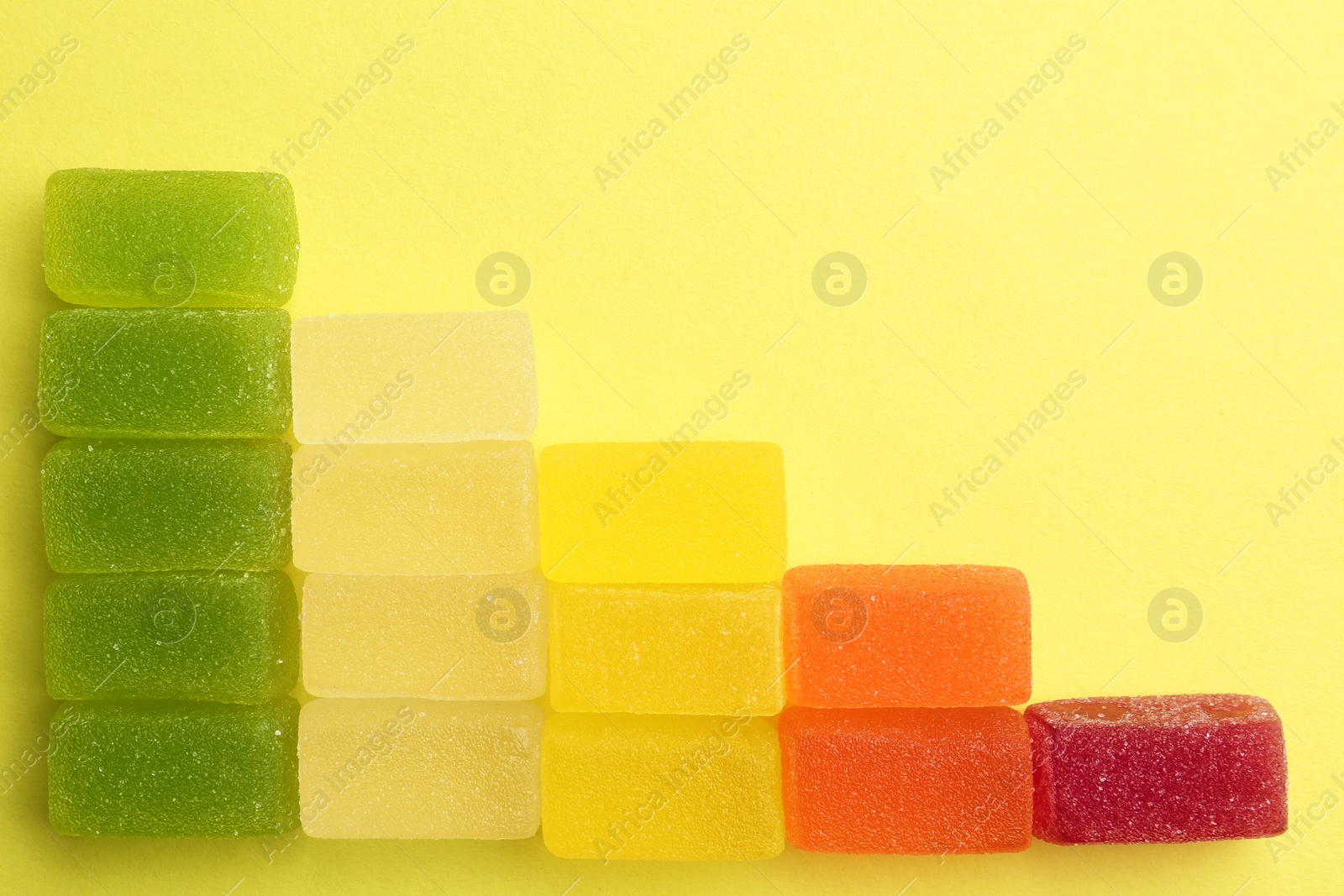 Photo of Flat lay composition with tasty bright jelly candies and space for text on color background