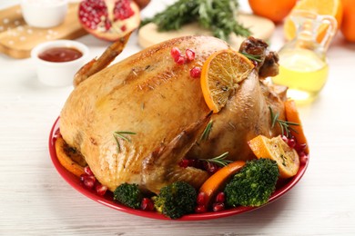 Delicious chicken with oranges and vegetables on white wooden table, closeup