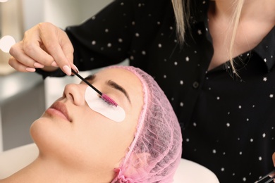 Young woman undergoing eyelash extensions procedure in salon