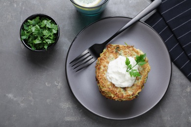 Delicious zucchini fritters served on grey table, flat lay