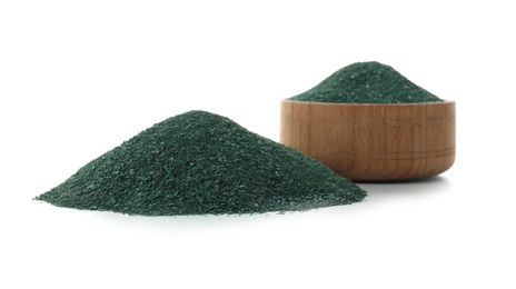 Photo of Bowl and heap of spirulina algae powder on white background