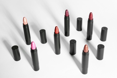 Photo of Set of bright lipsticks in black tubes on white background