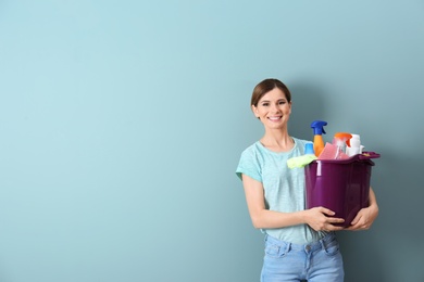 Photo of Woman holding bucket with cleaning supplies indoors