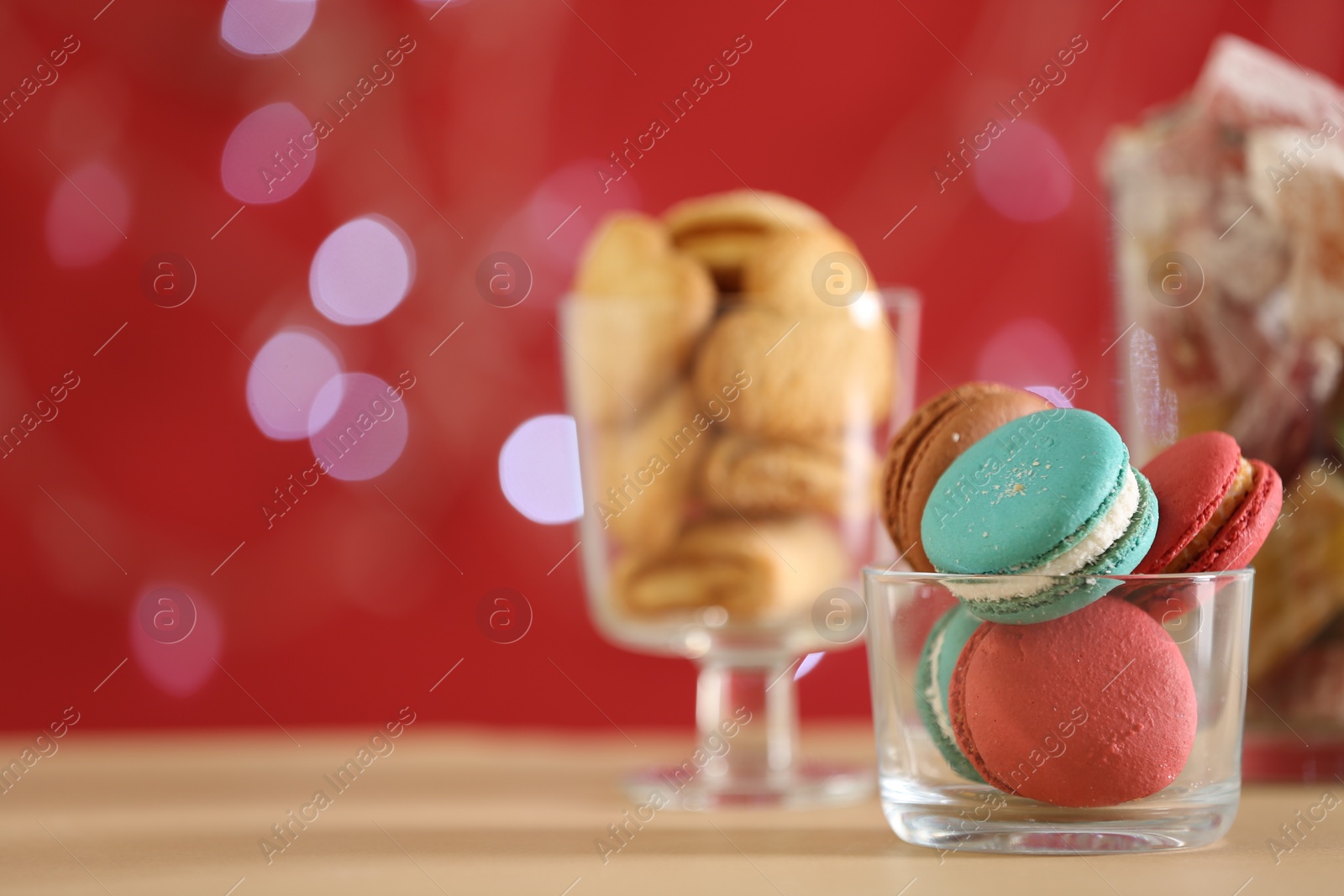 Photo of Delicious macarons in bowl on table against blurred background, closeup. Space for text