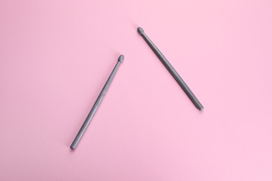 Two grey drumsticks on pink background, top view