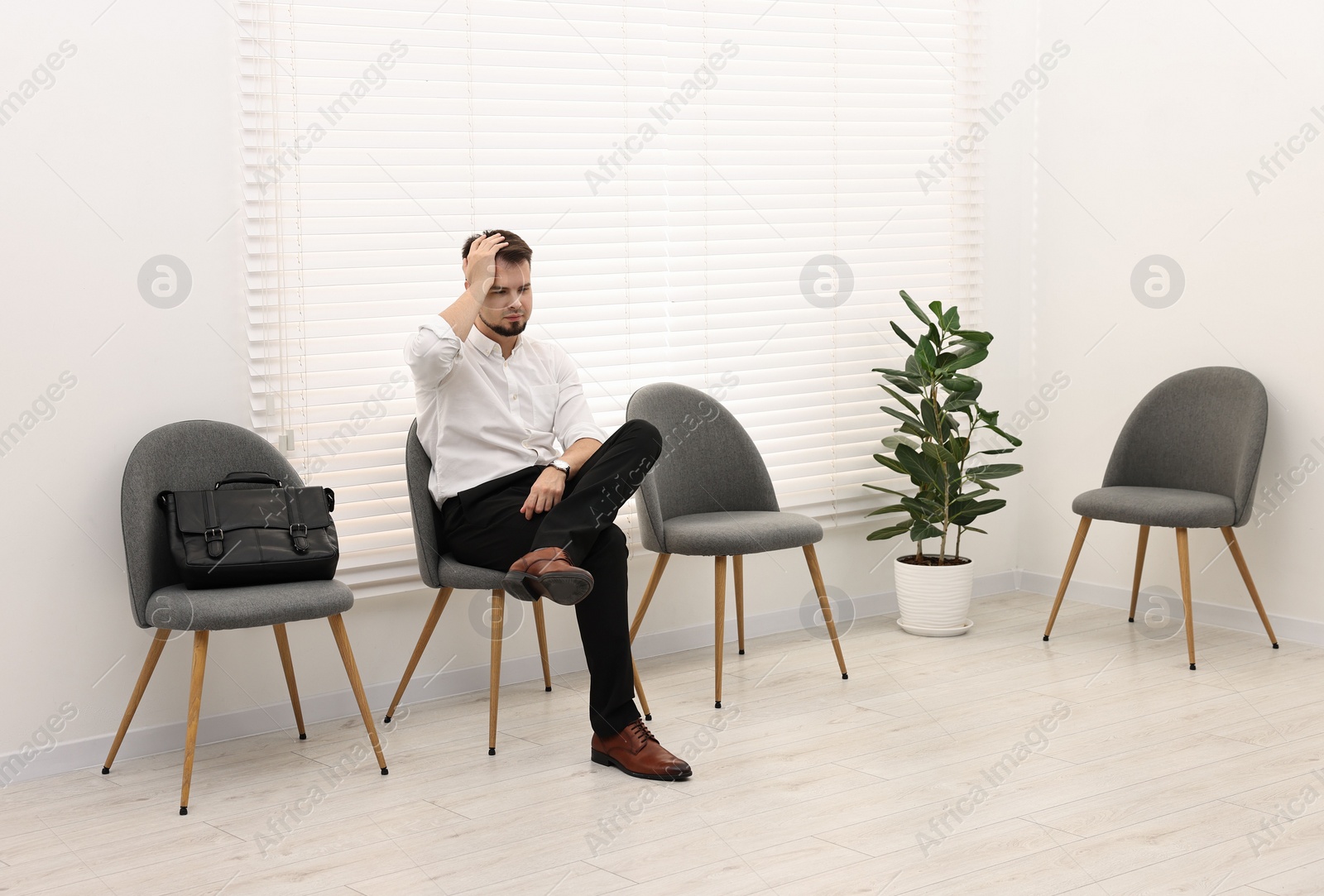 Photo of Man sitting on chair and waiting for job interview indoors