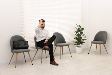 Man sitting on chair and waiting for job interview indoors