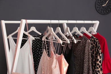 Photo of Wardrobe rack with women's clothes near dark wall