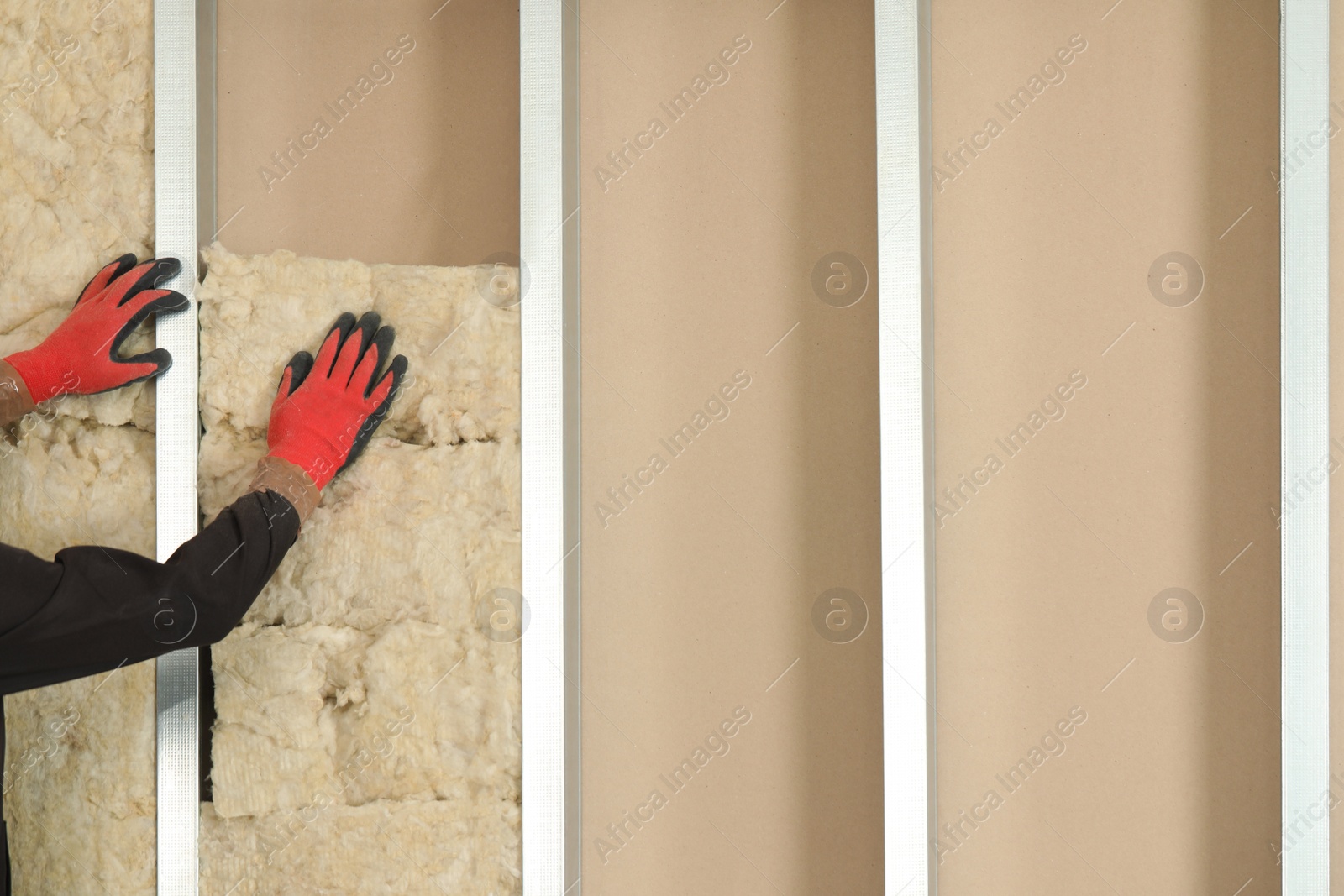 Photo of Worker installing thermal insulation material on wall, closeup