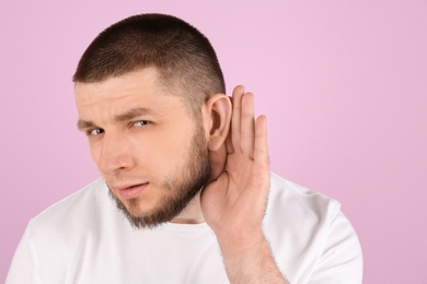 Photo of Young man with hearing problem on color background