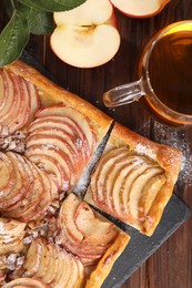 Photo of Freshly baked apple pie served with tea on wooden table, flat lay