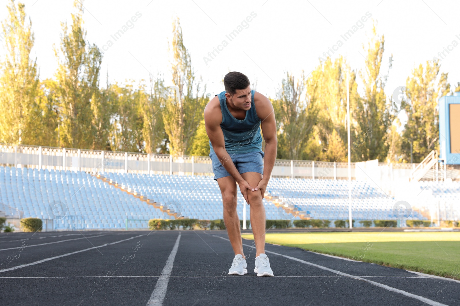 Photo of Man in sportswear having knee problems at stadium