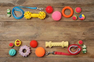 Photo of Flat lay composition with dog leashes and toys on wooden background, space for text