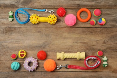 Flat lay composition with dog leashes and toys on wooden background, space for text