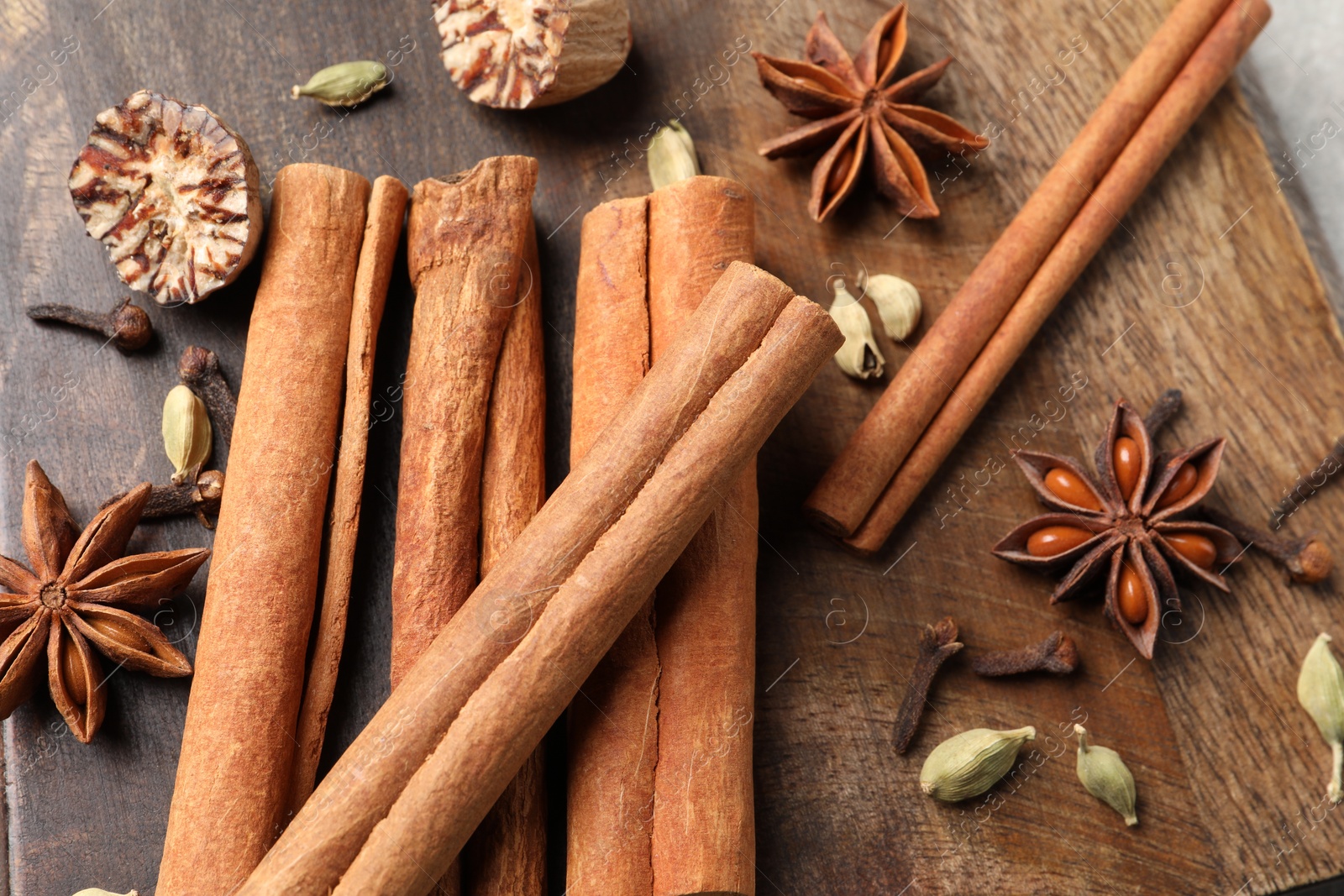 Photo of Different aromatic spices on wooden board, above view