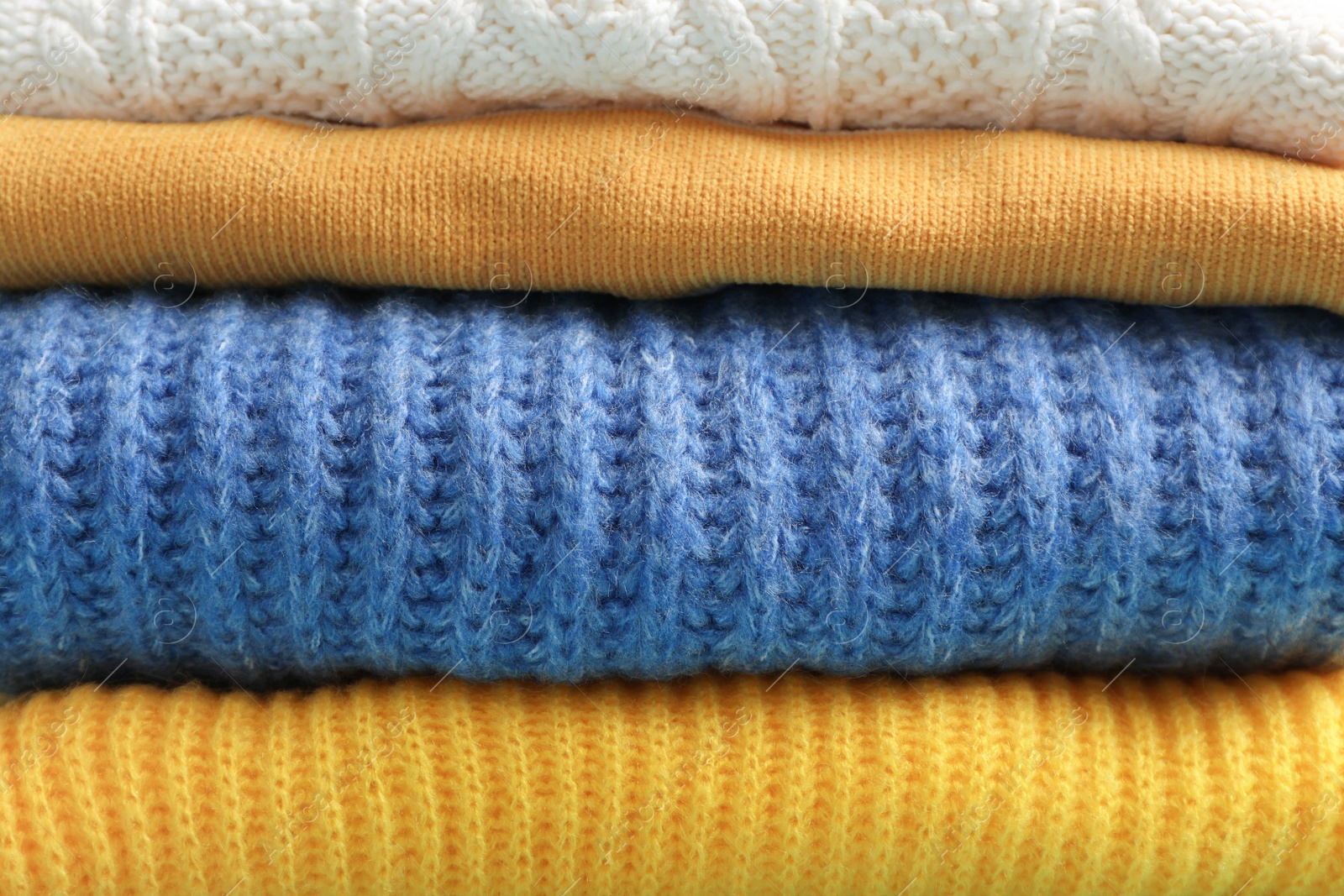 Photo of Stack of folded warm knitted sweaters, closeup