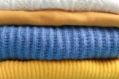 Photo of Stack of folded warm knitted sweaters, closeup