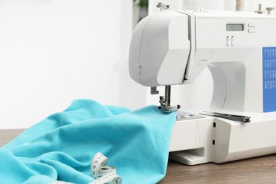 Photo of White sewing machine and cloth on wooden table indoors