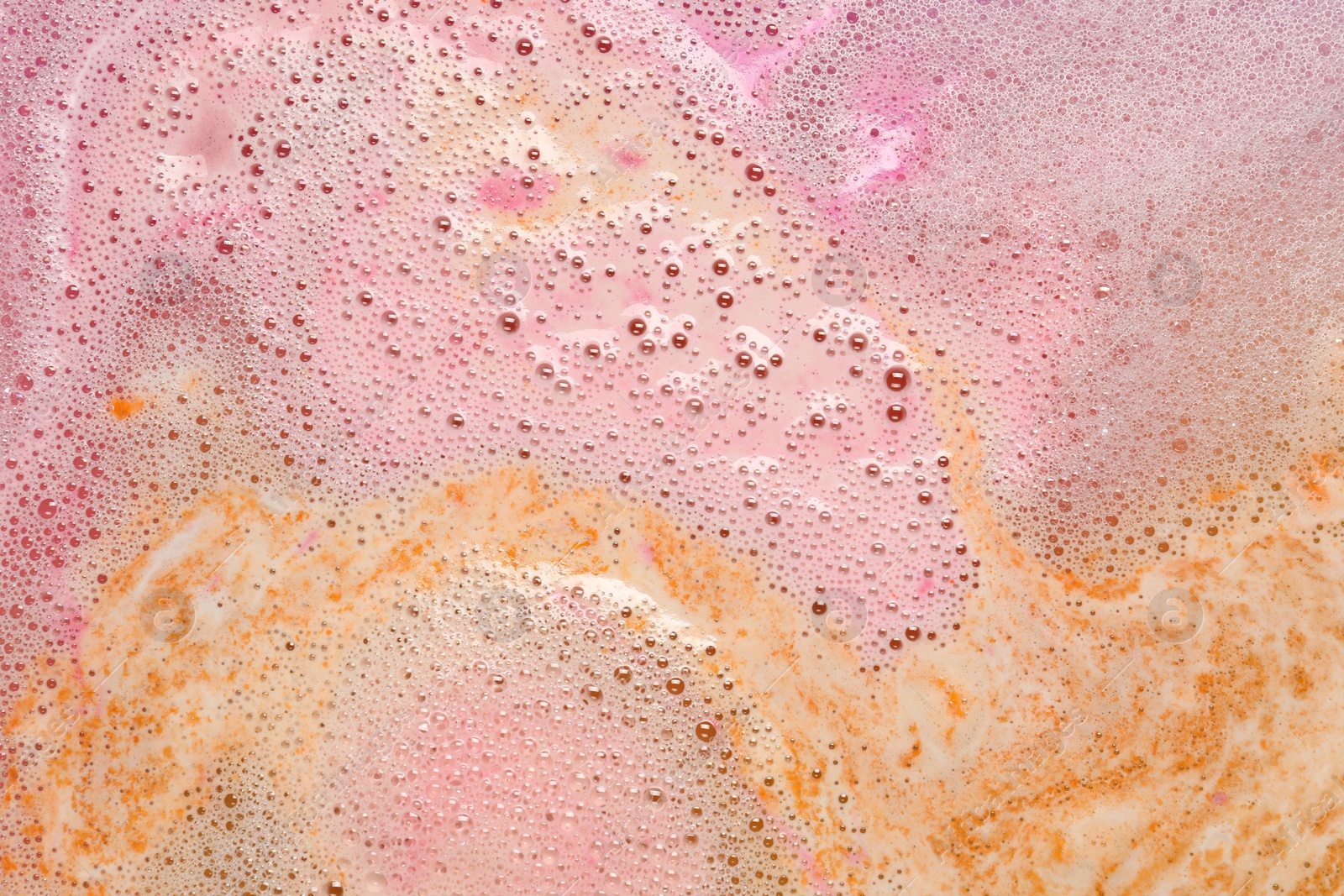 Photo of Colorful foam after dissolving bath bomb in water, closeup