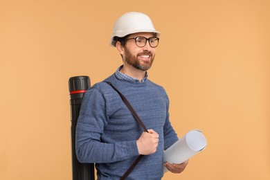 Photo of Architect in hard hat with drawing tube and draft on beige background