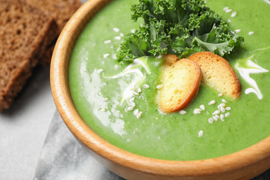Photo of Tasty kale soup with croutons on grey marble table, closeup