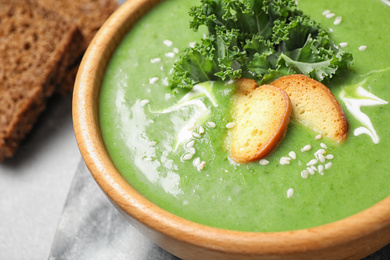 Tasty kale soup with croutons on grey marble table, closeup