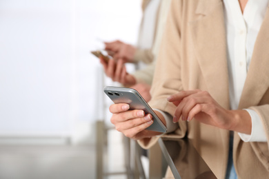 Photo of Young woman using modern smartphone indoors, closeup