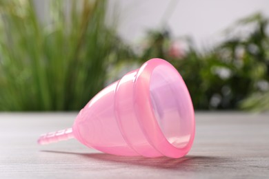 Pink menstrual cup on light table indoors, closeup